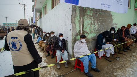 Afghan men line up as the UN World Food Program (WFP) distributes critical monthly food rations.