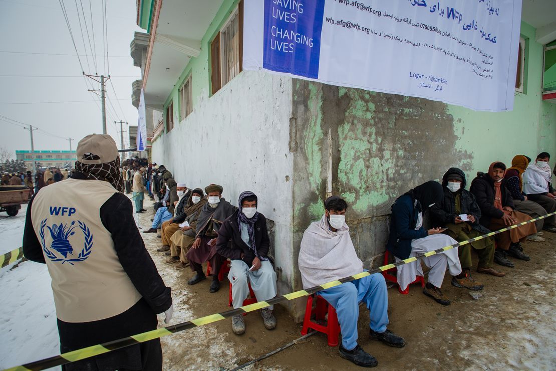 Afghan men line up as the UN World Food Program (WFP) distributes critical monthly food rations.