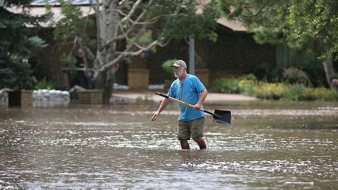 A resident of Flagstaff, Arizona, works to protect homes from floodwater that turned a cul-de-sac into a small lake, July 27, 2022.
