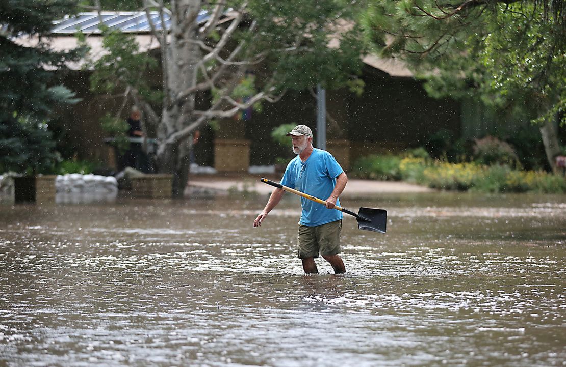A resident of Flagstaff, Arizona, works to protect homes from floodwater that turned a cul-de-sac into a small lake, July 27, 2022.