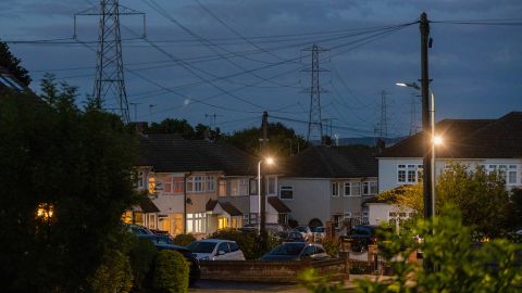 أبراج نقل الكهرباء بالقرب من المنازل السكنية مع إضاءة الأضواء في أبمينستر ، المملكة المتحدة ، يوم الاثنين ، 4 يوليو ، 2022. تستعد المملكة المتحدة لتقليل إحدى سياساتها الرئيسية المتعلقة بتغير المناخ في الوقت الذي تكافح فيه أسعار الطاقة المرتفعة التي ساهمت في تكلفة - أزمة معيشية لملايين المستهلكين. 
