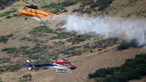 Two helicopters pass while fighting a wildfire in Springville, Utah, on August 1, 2022. 