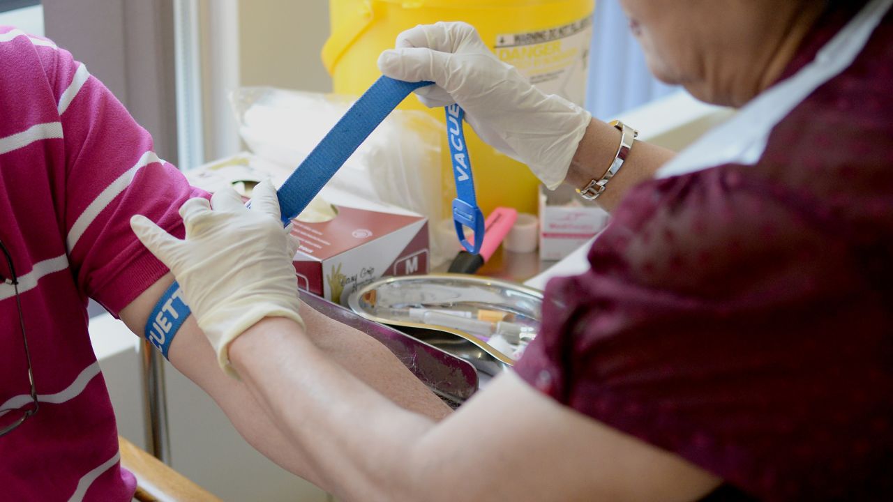 A nurse ties a tourniquet before taking blood at the Temple Fortune Health Centre GP Practice near Golders Green, London.
