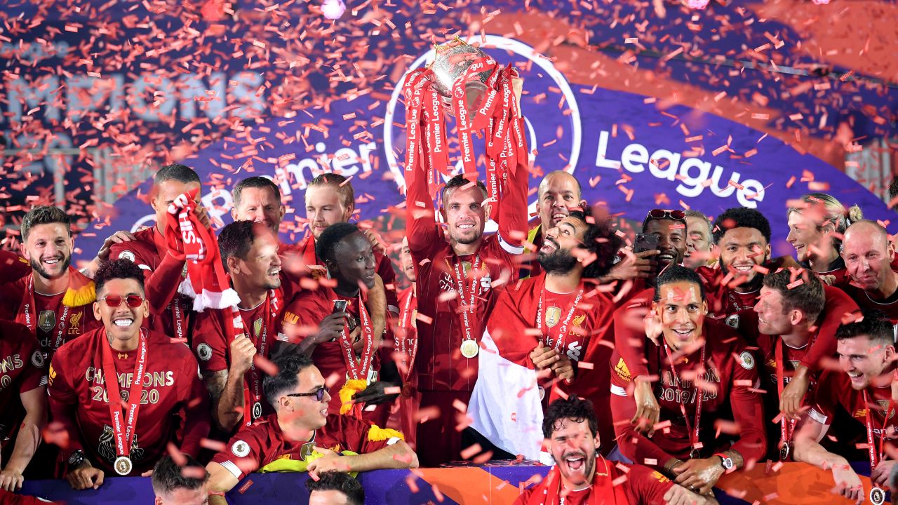Jordan Henderson lifts the Premier League trophy aloft alongside Mohamed Salah as they celebrate winning the league.