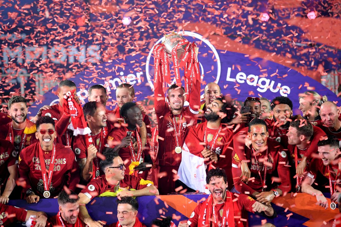 Jordan Henderson lifts the Premier League trophy aloft alongside Mohamed Salah as they celebrate winning the league.