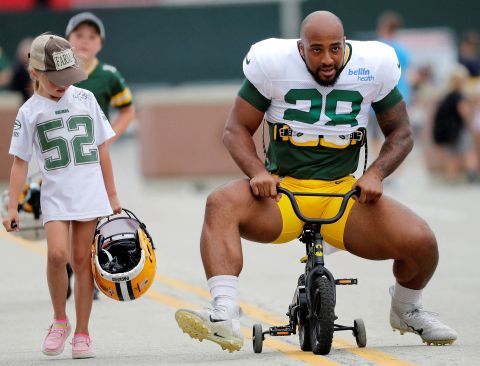 A young Green Bay Packers fan watches as running back AJ Dillon tries to ride her bicycle to training camp on Monday, August 1. It is a tradition at Packers camp for children to lend their bikes to players.