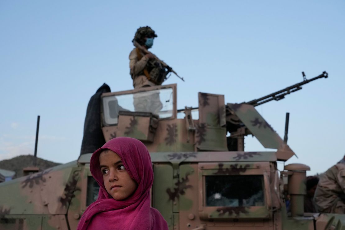 An Afghan girl stands by a Taliban fighter in Paktika province, Afghanistan, Saturday, June 25, 2022. 