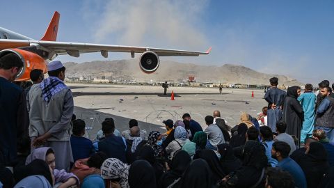 Afghan people wait to leave Kabul's airport on August 16, 2021, a day after the Taliban takeover. 