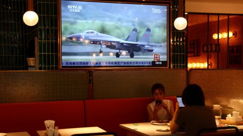 أشخاص يتناولون العشاء في مطعم في بكين بالقرب من شاشة تعرض لقطات إخبارية للتدريبات العسكرية بالقرب من تايوان ، 5 أغسطس ، 2022. 
