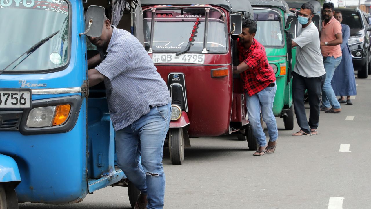 Sri Lankan three-wheeler drivers push their vehicles along the queue near a fuel station in Colombo, Sri Lanka, on Aug. 2. The island nation faces a grave fuel shortage due to the lack of foreign currency.