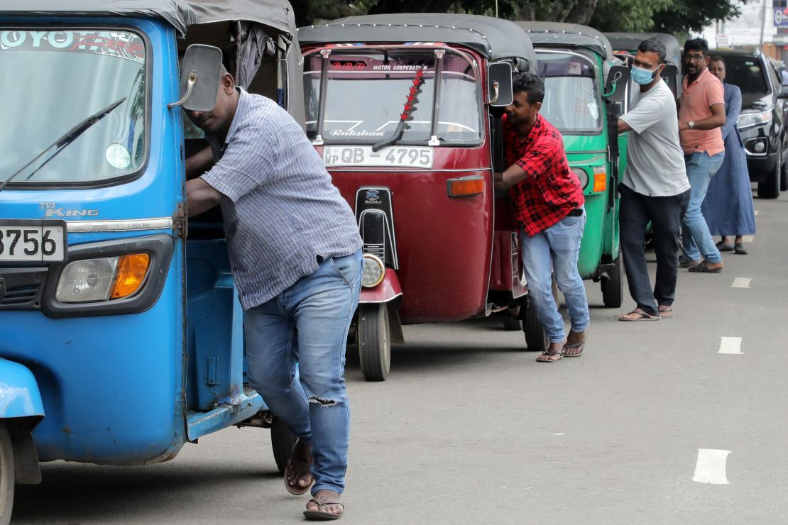 Sri Lankan three-wheeler drivers push their vehicles along the queue near a fuel station in Colombo, Sri Lanka, on Aug. 2. The island nation faces a grave fuel shortage due to the lack of foreign currency.