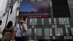 People in Beijing walk in front of a large screen showing a news broadcast about China's military exercises near Taiwan on August 4.