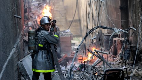 2022 年 8 月 5 日、ガザ市へのイスラエルの空爆後の破壊の中で炎と戦うパレスチナの消防士。