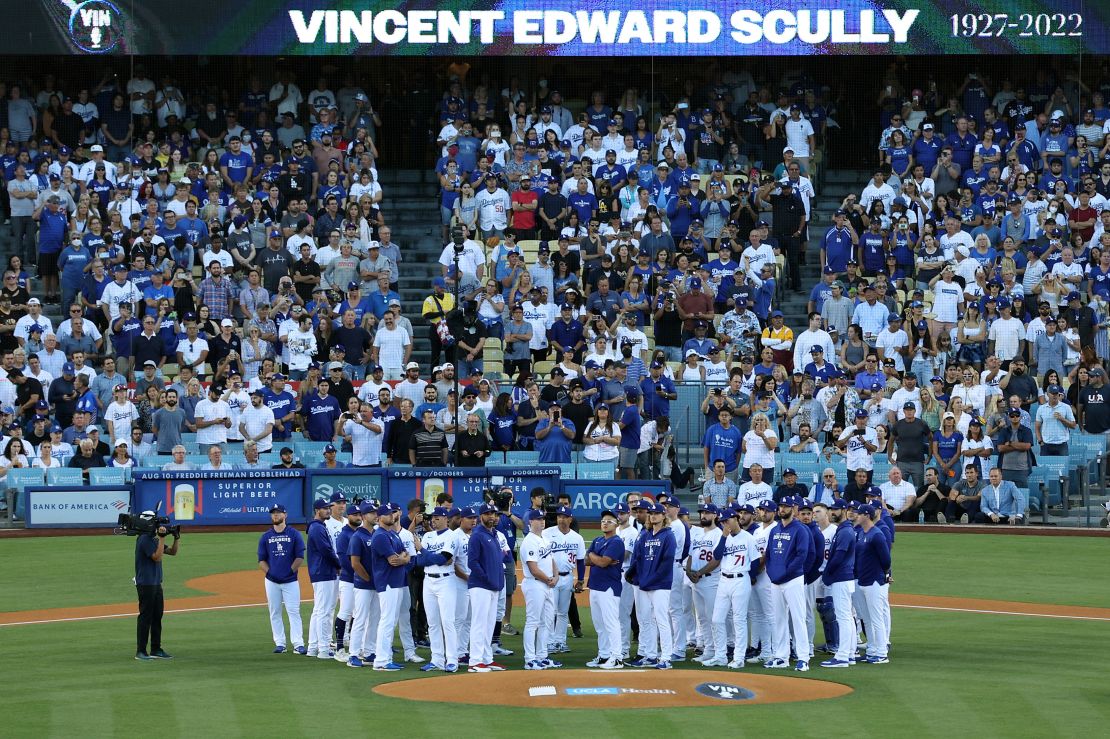 Los Angeles Dodgers players and coaches stand on the field as Vin Scully is honored during a pregame ceremony.