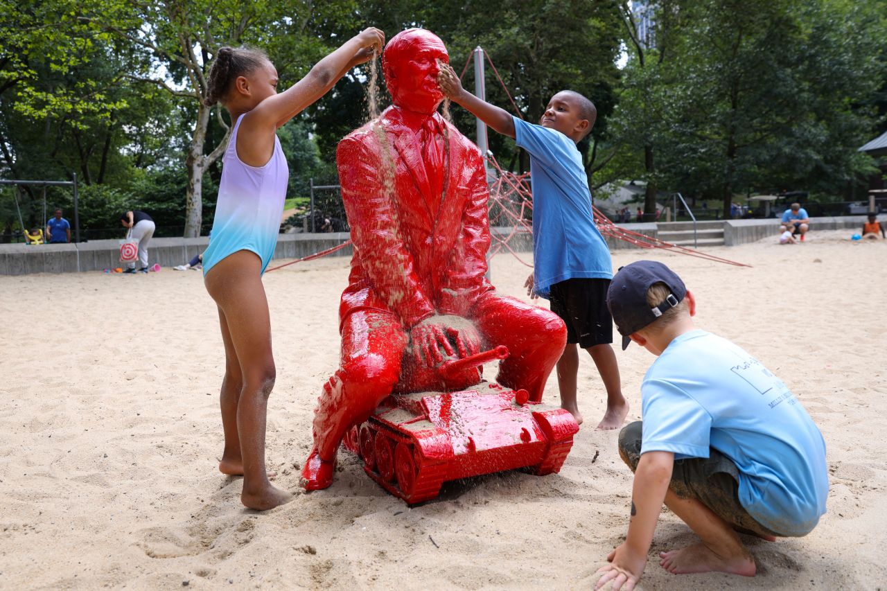 Children cover a statue of Russian President Vladimir Putin with sand in Central Park.