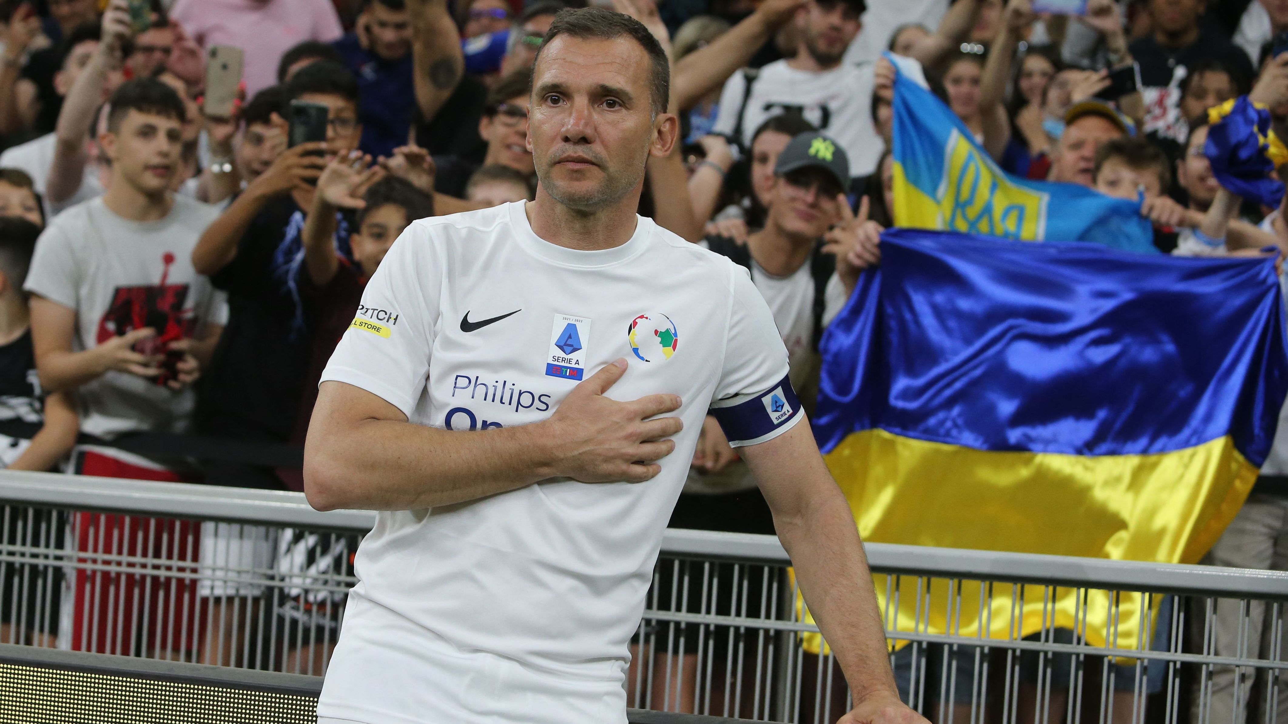 Former Ukranian forward Andriy Shevchenko poses next to the Ukrainian flag during a charity match. 