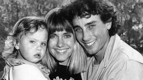 Newton-John holds her daughter, Chloe, as she arrives at a Sydney airport with her first husband, Matt Lattanzi, in 1987.