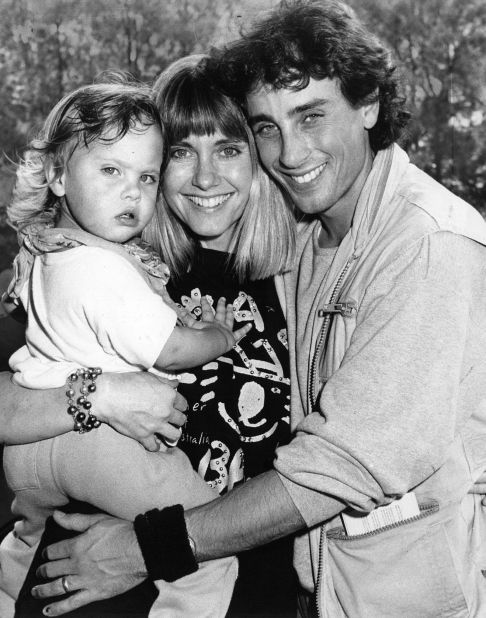 Newton-John holds her daughter, Chloe, as she arrives at a Sydney airport with her first husband, Matt Lattanzi, in 1987.