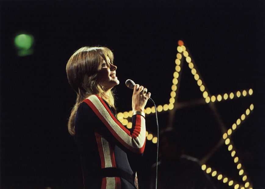 Newton-John performs on the British TV show "Top of the Pops" in striped jumpsuit. 