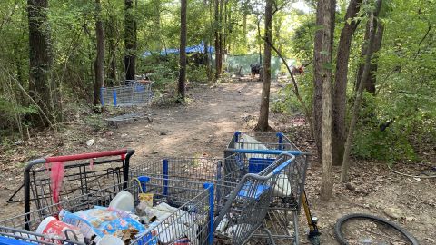 A homeless encampment in Nashville is littered with shopping carts and trash.
