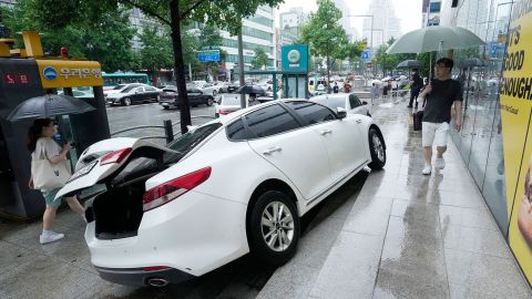 Ein Fahrzeug wird auf einem Bürgersteig beschädigt, nachdem es am 9. August in Seoul, Südkorea, bei starkem Regen geschwommen war.