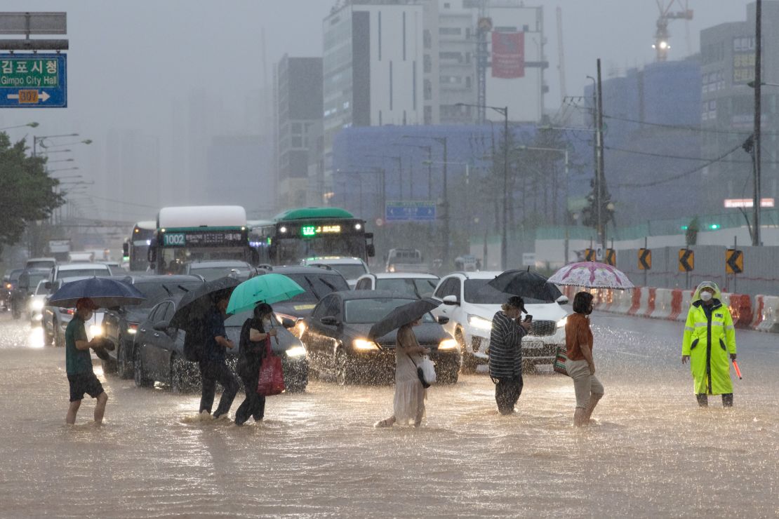 Pedestrians cross a flooded road in Gimpo, Seoul, on August 9.