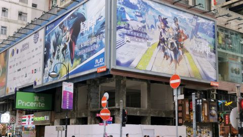People walk below a billboard ad of fantasy game "Genshin Impact" from Shanghai-based developer miHoYo in Hong Kong, China October 20, 2020.  The game has been powered by Unity's software tools.