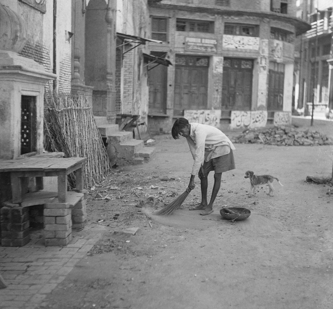 A street sweeper at work after communal riots in Amritsar, Punjab, during the Partition of  India, 1947. The streets are otherwise deserted under a curfew imposed by the British Army.