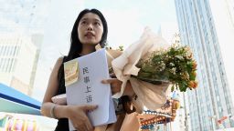 Zhou Xiaoxuan, also known as Xianzi, a feminist figure who rose to prominence during China's #MeToo movement, holds a bouquet of flowers as she arrives to attend a hearing in her sexual harassment case against prominent television host Zhu Jun at the Beijing No. 1 Intermediate People's Court in Beijing on August 10, 2022. (Photo by Noel Celis / AFP) (Photo by NOEL CELIS/AFP via Getty Images)