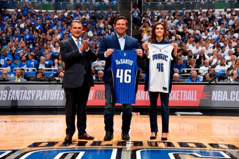 DeSantis and his wife hold up Orlando Magic jerseys before an NBA playoff game in 2019.