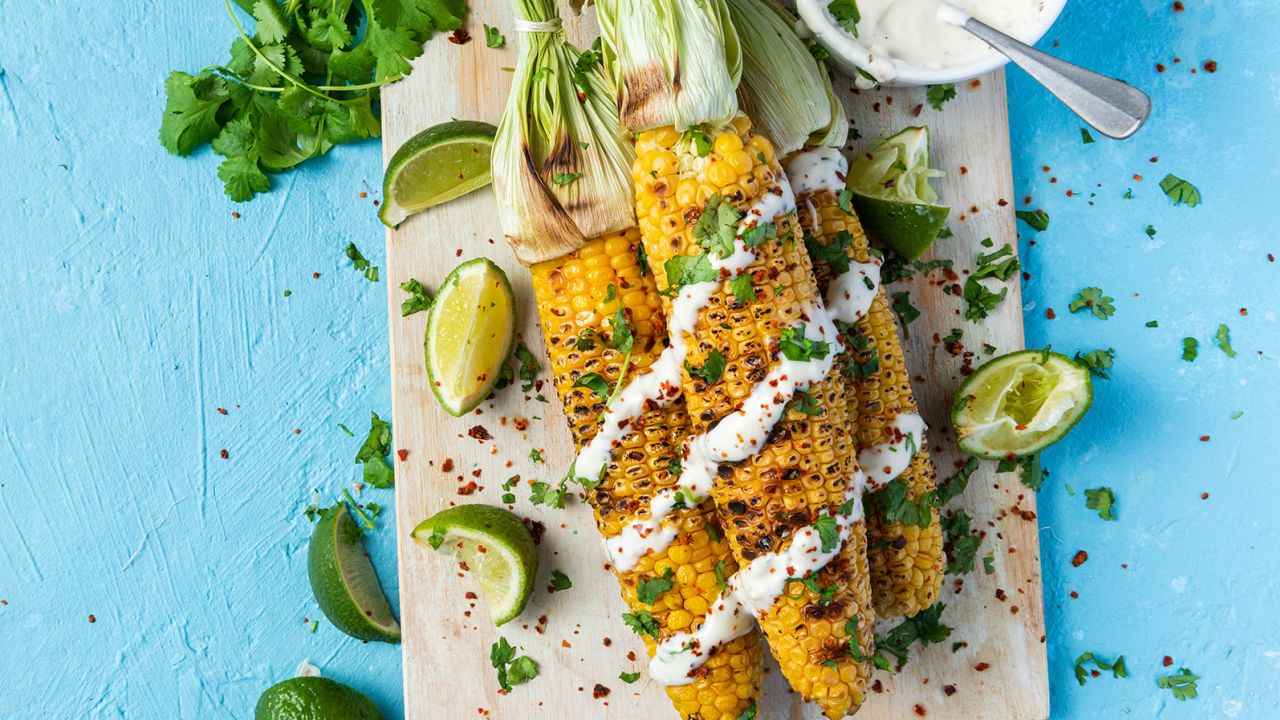 Grilled barbecue corn on the cob with herbs, limes and garlic sauce makes for a tasty summer snack.