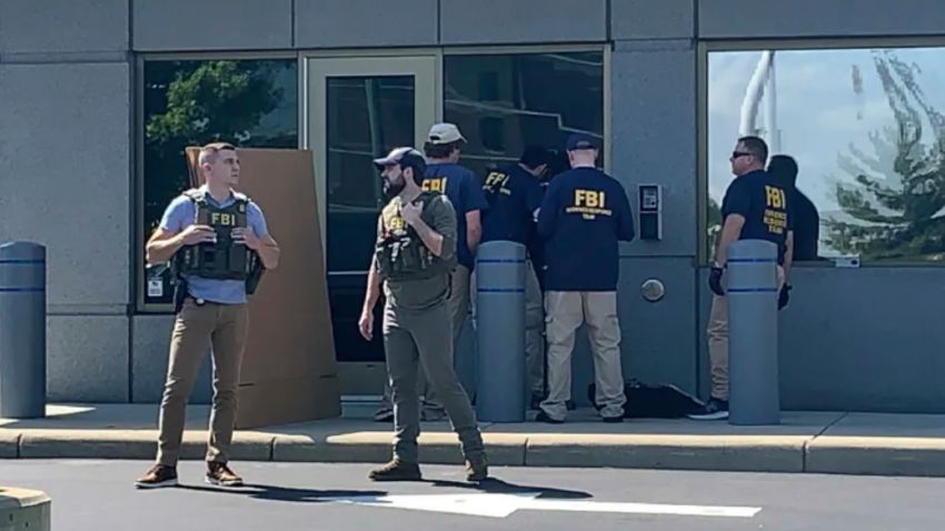 In this image taken from FOX19 Cincinnati video, FBI officials gather outside the FBI building in Cincinnati, Thursday, Aug. 11, 2022. An armed man decked out in body armor tried to breach a security screening area at the FBI field office in Ohio on Thursday, then fled and exchanged gunfire in a standoff with law enforcement, authorities said. 