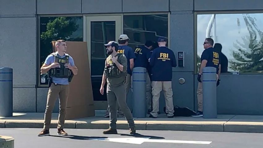 In this image taken from FOX19 Cincinnati video, FBI officials gather outside the FBI building in Cincinnati, Thursday, Aug. 11, 2022. An armed man decked out in body armor tried to breach a security screening area at the FBI field office in Ohio on Thursday, then fled and exchanged gunfire in a standoff with law enforcement, authorities said.