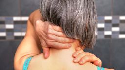 woman in pain rubbing neck