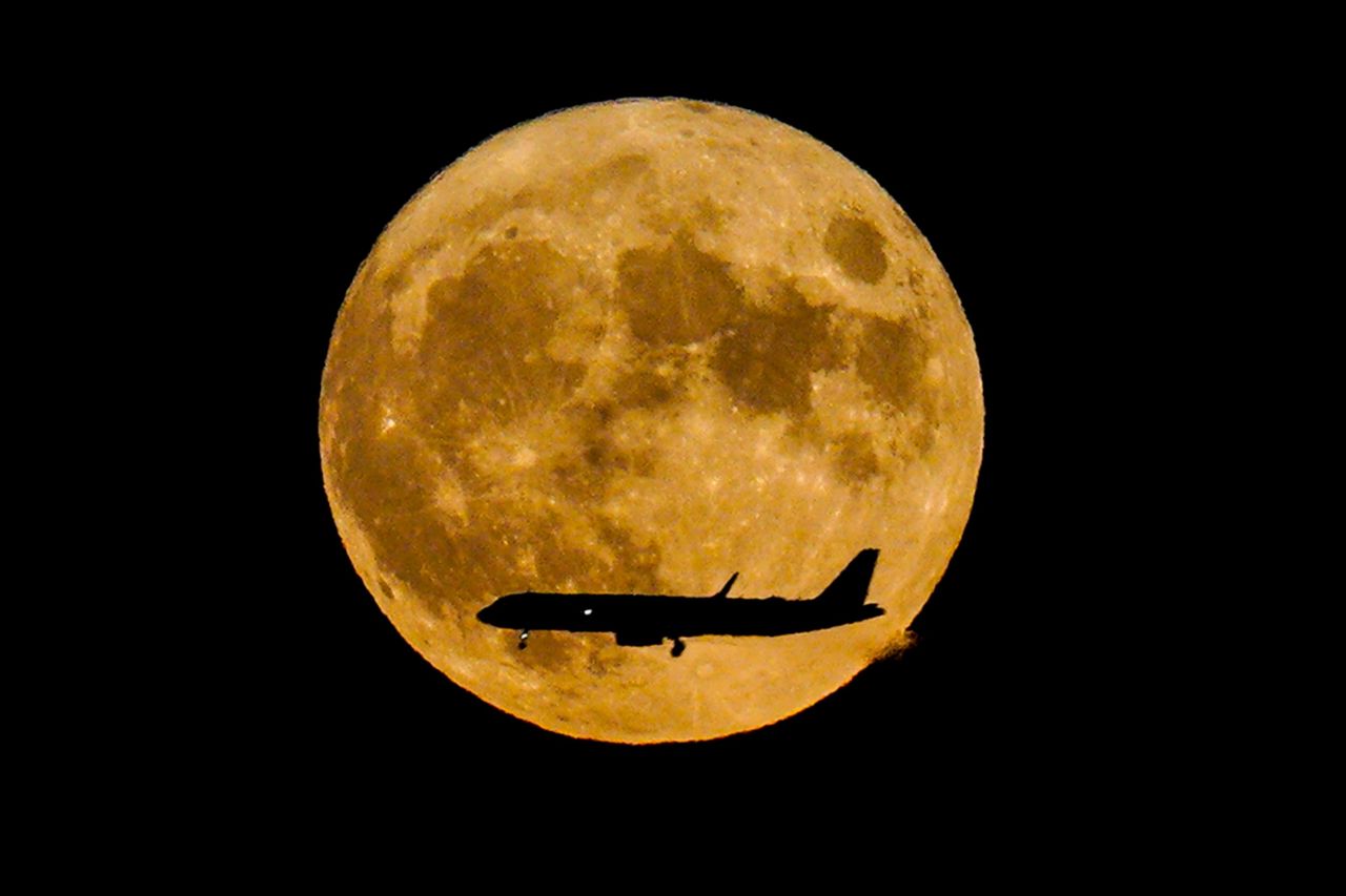 The supermoon — also called the sturgeon moon — rises as a jetliner approaches John F. Kennedy International airport on August 11 in New York City.