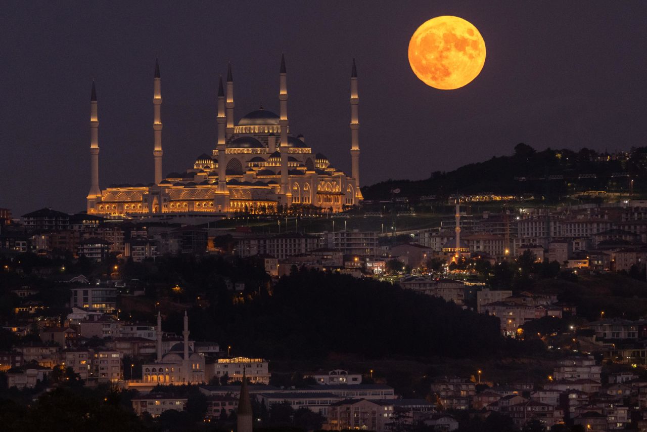 The sturgeon full moon rises next to Istanbul's Çamlica Mosque on August 11.