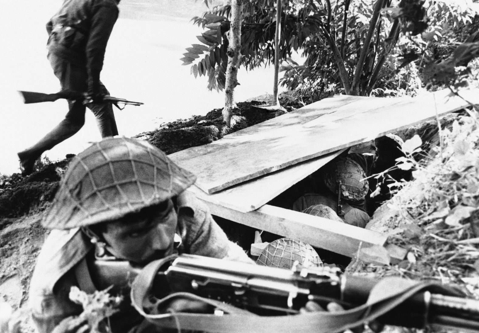 A Pakistani soldier aims his rifle, while a fellow soldier runs for cover during Indian shelling of Pakistani positions in East Pakistan on December 2, 1971. A third war between India and Pakistan in East Pakistan ends with the creation of Bangladesh.