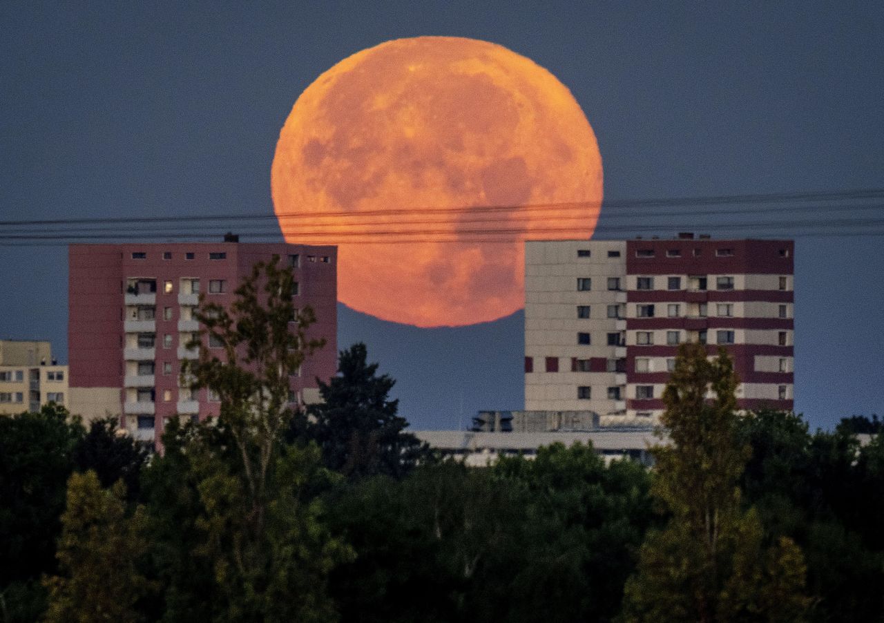 The full moon sets behind apartment houses in the outskirts of Frankfurt, Germany, early Friday, August 12.