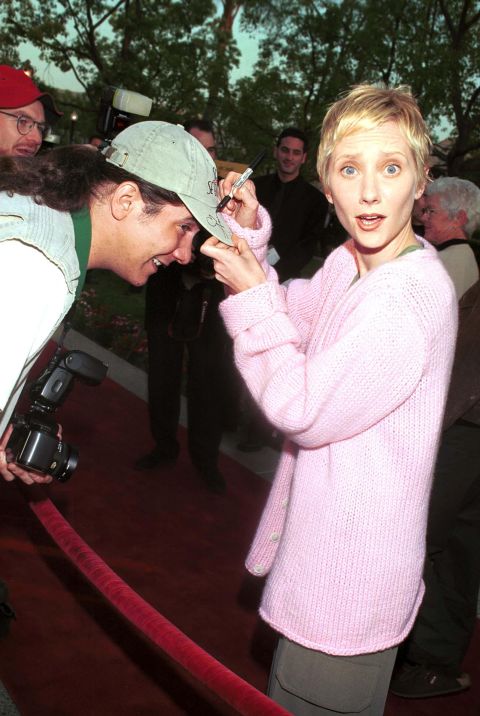 Heche signs a fan hat at the 