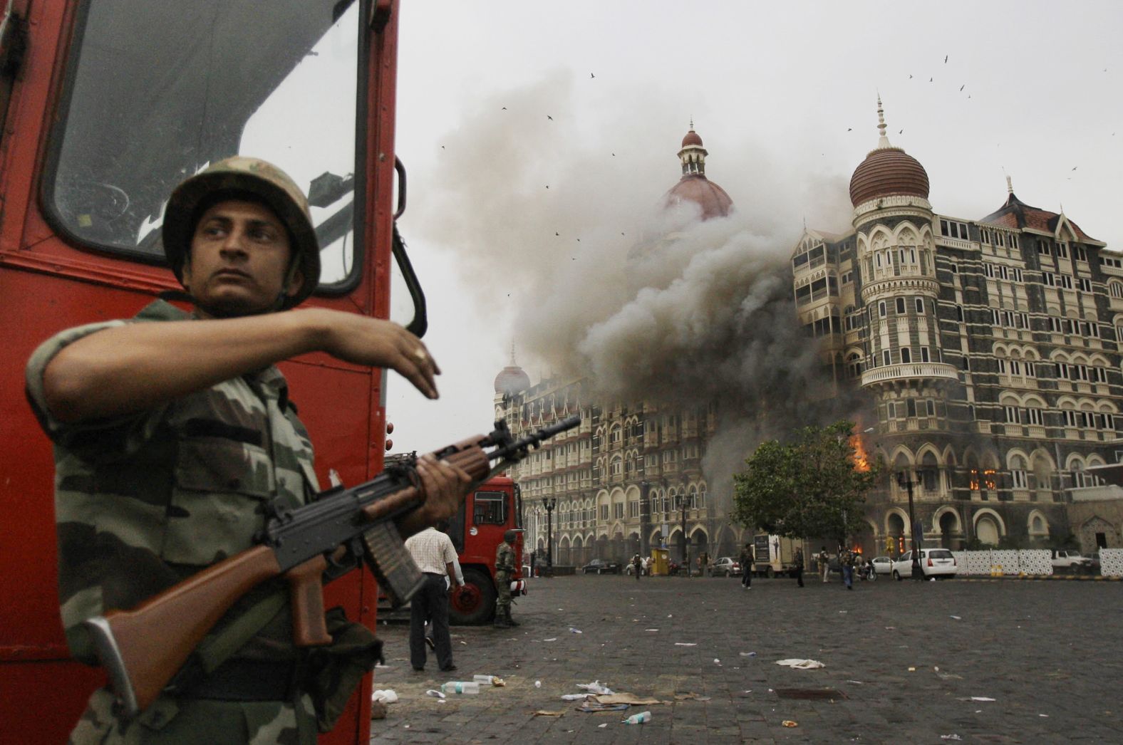 An Indian soldier takes cover as the Taj Hotel burns during gun battle between Indian military and militants inside in Mumbai, India on November 29, 2008. Ten Pakistani men associated with the terror group Lashkar-e-Tayyiba stormed buildings in Mumbai, killing 164 people. 