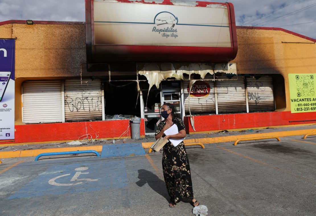 A woman stands in front of a building that was burnt during violence that swept across parts of Ciudad Juarez.