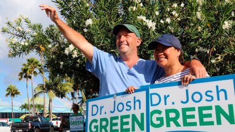 Hawaii Lt. Gov. Josh Green, left, and his wife, Jamie, greet passing cars while campaigning in Honolulu on Aug. 2, 2022. The candidates running in Hawaii's primary election to succeed term-limited Democratic Gov. David Ige include a former first lady, a retired mixed martial arts champion and a congressman who moonlights as a Hawaiian Airlines pilot. (AP Photo/Audrey McAvoy)