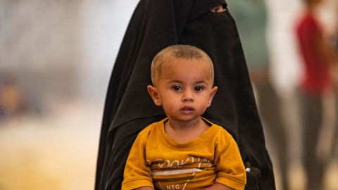 A woman carries her child as people wait to be released from the Kurdish-run al-Hol camp, which holds relatives of suspected Islamic State (ISIS) fighters, in Syria's northeastern Hasakeh governorate on August 14.