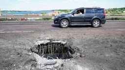 TOPSHOT - A picture taken on July 21, 2022 shows a car moving past a crater on Kherson's Antonovsky (Antonivskiy) bridge across the Dnipro river caused by a Ukrainian rocket strike, amid the ongoing Russian military action in Ukraine. (Photo by STRINGER / AFP) (Photo by STRINGER/AFP via Getty Images)