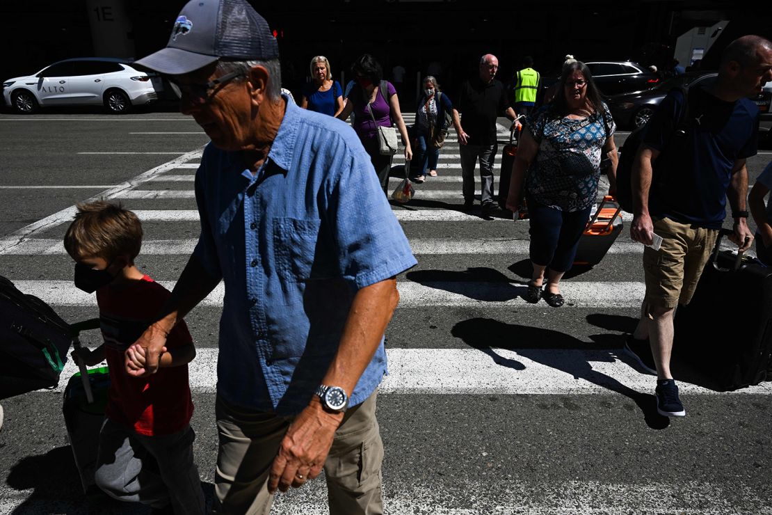 Passengers carry baggage across a street to a parking garage at Los Angeles International Airport. While no one knows for certain what lies ahead for flight disruptions, airfares are definitely down.