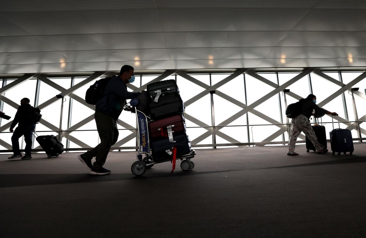 Travelers walk with their luggage at San Francisco International Airport on July 1, 2022. Fewer people are expected to be flying this fall compared with this past summer. And Labor Day weekend airfares are down.