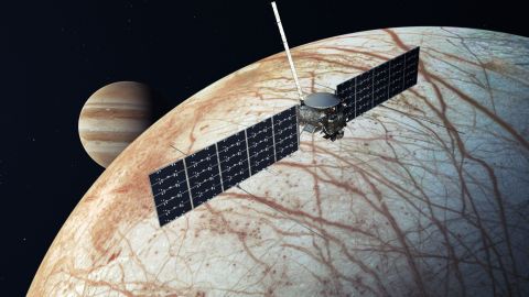 This illustration shows Europa Clipper making a flyby of the icy moon, with Jupiter in the background. 