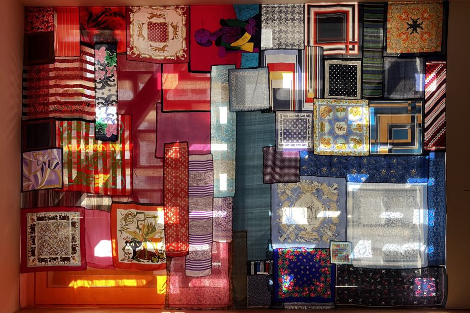 Rist plays with perceptions of light, and many of the exhibits sources of natural light, such as "Welcome in Any Sense" (2022), which uses scarves in a colorful patchwork quilt across the window. 