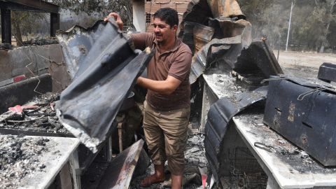 A man checks burnt objects following raging fires in Algeria's city of el-Kala on August 17, 2022.  