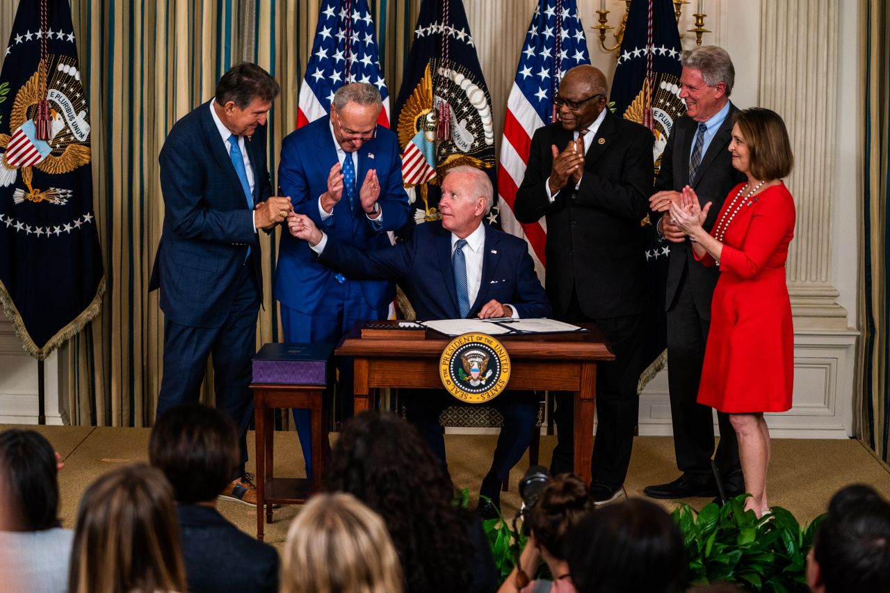 US President Joe Biden hands Sen. Joe Manchin the pen used to sign the Inflation Reduction Act at the White House on Tuesday, August 16. Also pictured from left are Senate Majority Leader Chuck Schumer, House Majority Whip Rep. Jim Clyburn, Rep. Frank Pallone and Rep. Kathy Castor.